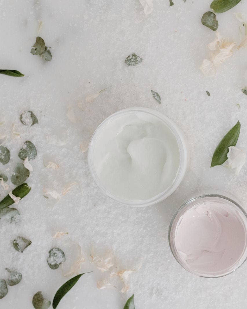 Two small pots of cream among scattered eucalyptus leaves.