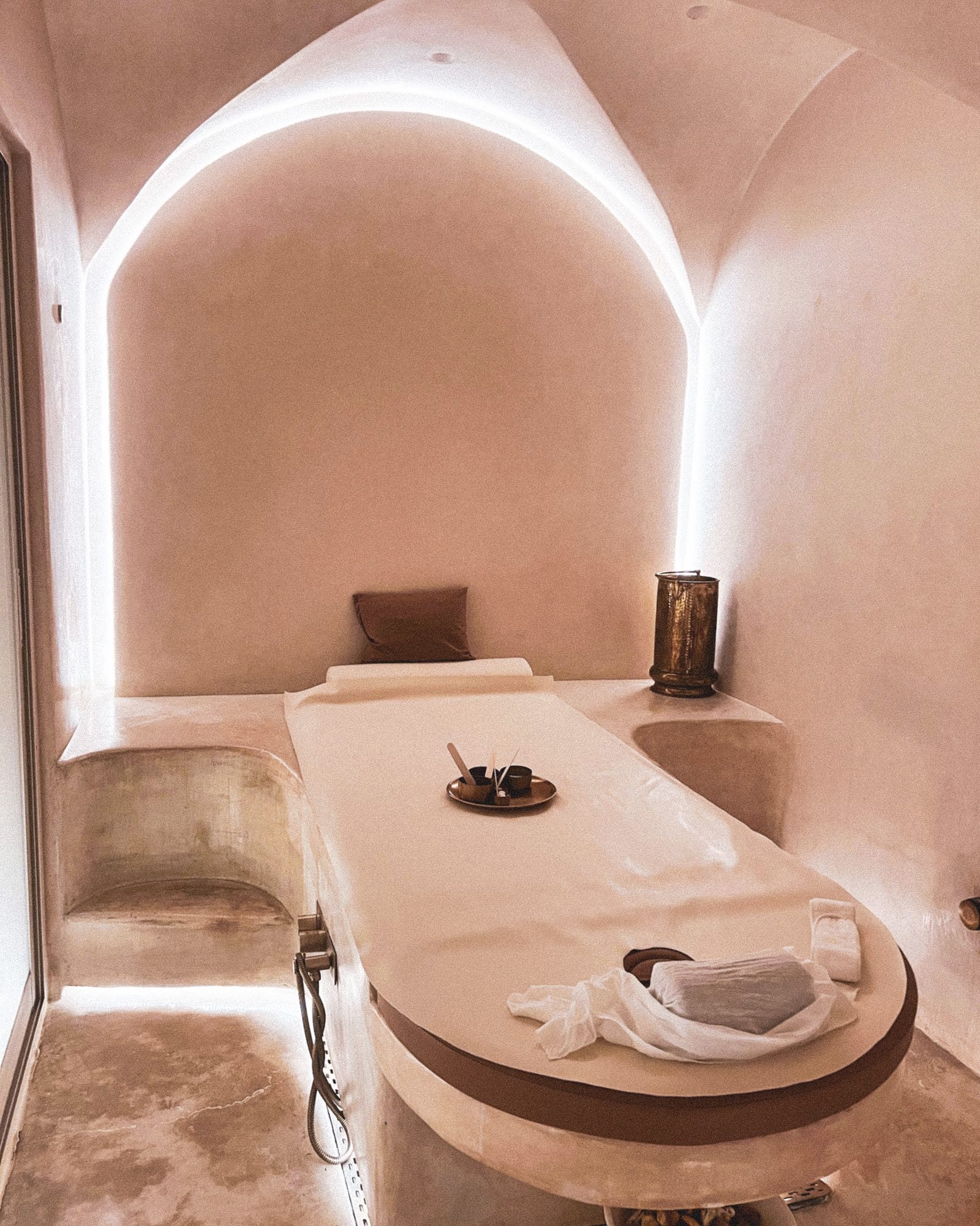 A quiet treatment room with a vaulted ceiling, soft light and a single couch.